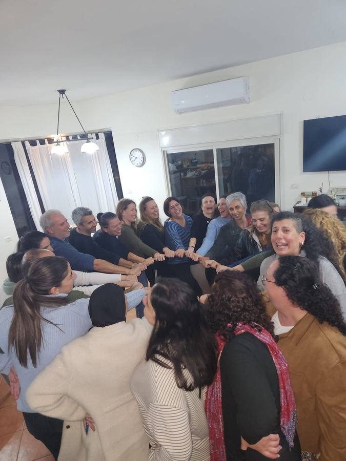 צוות בתרגיל שרשרת ידיים בסלון ביתי