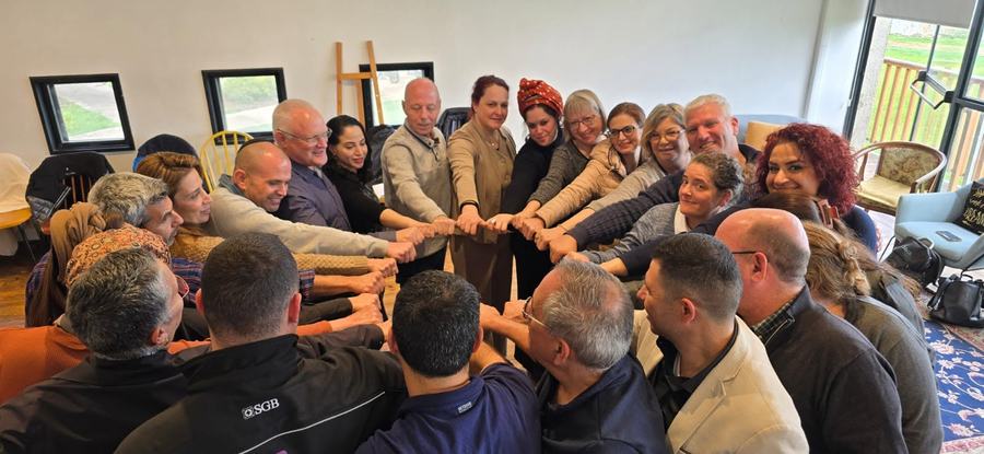 משתתפים בסדנת גיבוש יוצרים שרשרת ידיים משותפת